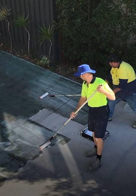 Workers applying a new finish to a concrete driveway